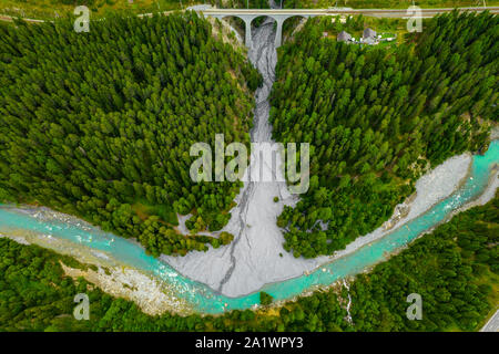 Inn fiume che scorre nella foresta in Svizzera. Vista aerea da fuco su un vecchio ponte ferroviario viadotto in montagna Foto Stock