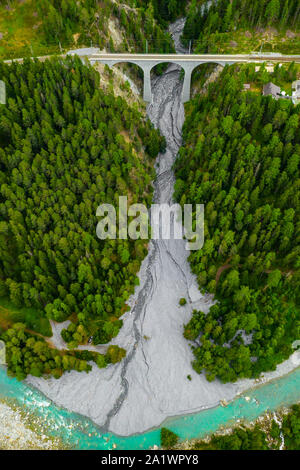 Inn fiume che scorre nella foresta in Svizzera. Vista aerea da fuco su un vecchio ponte ferroviario viadotto in montagna Foto Stock