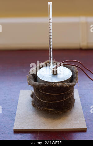 Capacità di calore specifico di esperimento di alluminio impostato con isolamento. Il blocco di alluminio con un riscaldatore ad immersione e termometro su un tappetino resistente al calore Foto Stock