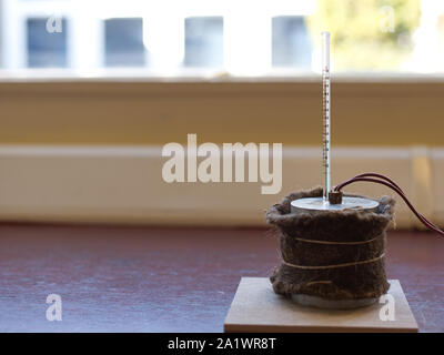 Capacità di calore specifico di esperimento di alluminio impostato con isolamento. Il blocco di alluminio con un riscaldatore ad immersione e termometro su un tappetino resistente al calore Foto Stock