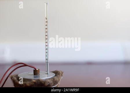 Capacità di calore specifico di esperimento di alluminio impostato con isolamento. Il blocco di alluminio con un riscaldatore ad immersione e termometro su un tappetino resistente al calore Foto Stock