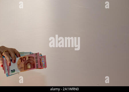 Le banconote in euro tenendo in mano, sfondo bianco Foto Stock