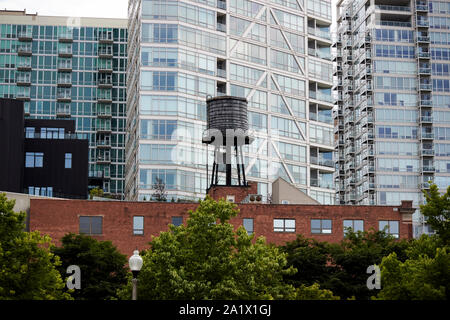 Vecchio di acqua di legno sulla torre di mattoni rossi vicino a mongomery ward erie park con il nuovo alto luogo di edifici residenziali dietro di Chicago in Illinois regno sta Foto Stock