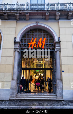 Atene, Grecia - 4 Gennaio 2019: entrata di un HM store durante la notte con le persone intorno a Atene, Grecia Foto Stock