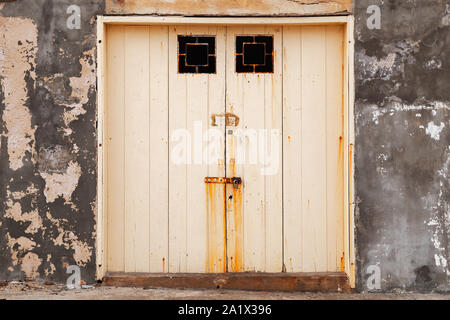 Chiuso giallo antico cancello in grungy parete in cemento, vista frontale Foto Stock