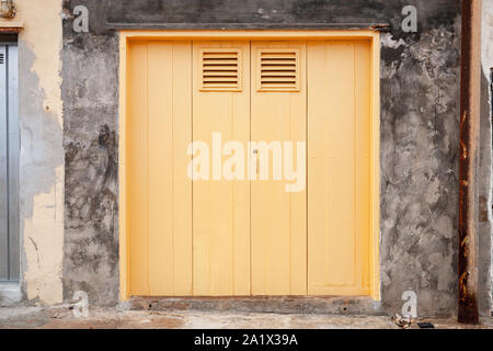 Chiuso giallo antico cancello in grungy muro di pietra, vista frontale Foto Stock