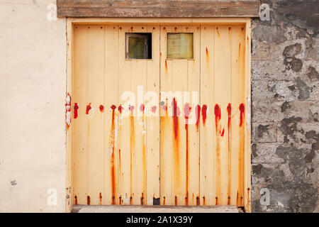 Chiuso giallo antico cancello con piccole finestre in grungy parete in cemento, vista frontale Foto Stock
