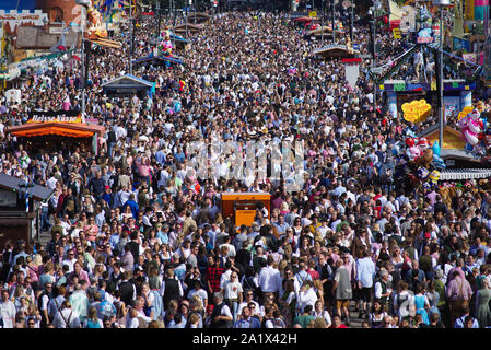 Un grande numero di visitatori di passeggiare in una domenica / weekend lungo uno dei viali principali di Oktoberfest a Theresienwiese, Monaco di Baviera, Germania. Foto Stock