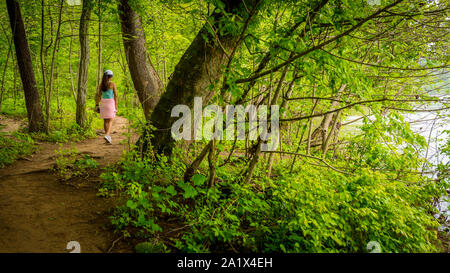 Medioevo donna con rosa maglione legato attorno la sua vita camminando sul sentiero nel Parco Nazionale Foto Stock
