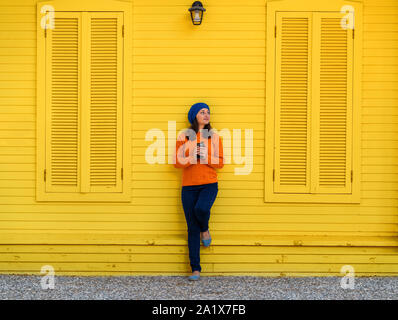 Giovane donna beve caffè con berretto blu per esterno Foto Stock