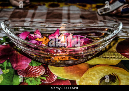 Un vaso è che è caricata con rose e candela su indian festival diwali deepawali con il fuoco isolato sul tavolo Foto Stock