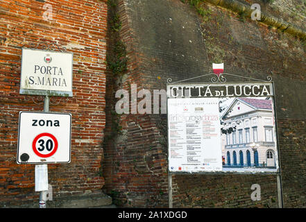 Close-up di nome segno della Porta Santa Maria della porta della città e di un segno comunale con il programma del Teatro del Giglio, Toscana, Italia Foto Stock