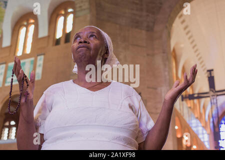 Aparecida, São Paulo, Brasile - 13 Gennaio 2016: Fedeli Afro -donna brasiliana prega alla cattedrale di Nossa Senhora Aparecida Santuario Nazionale Foto Stock