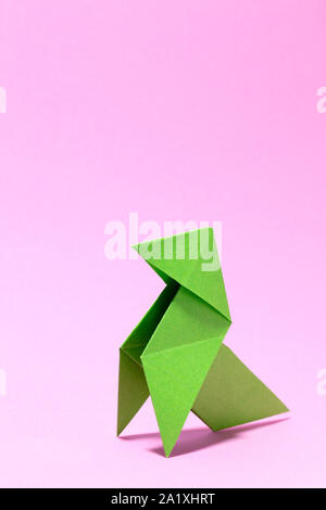 Classico verde uccello di carta origami in rosa colore di sfondo, con spazio libero per il testo sul lato superiore, alta cartoon di consistenza e di grandi dimensioni Foto Stock