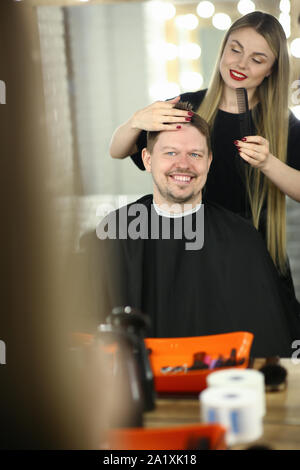 Donna Barbiere rendendo taglio di capelli per uomo sorridente Client Foto Stock