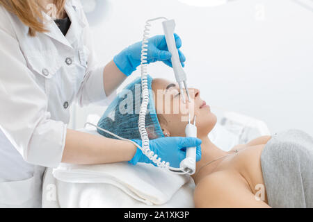 Ritratto di una giovane ragazza bella faccia terapia microcurrent procedura. Cura del viso e il ringiovanimento. Aumento del tono epidermico. Foto Stock