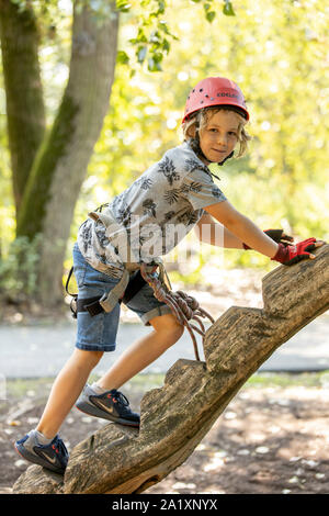 Falesia, corso di arrampicata, boy, 9 anni, con il casco e il cablaggio a un corso di arrampicata in una foresta, Foto Stock