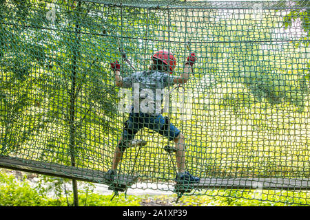 Falesia, corso di arrampicata, boy, 9 anni, con il casco e il cablaggio a un corso di arrampicata in una foresta, Foto Stock