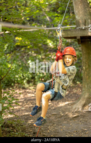 Falesia, corso di arrampicata, boy, 9 anni, con il casco e il cablaggio a un corso di arrampicata in una foresta, Foto Stock