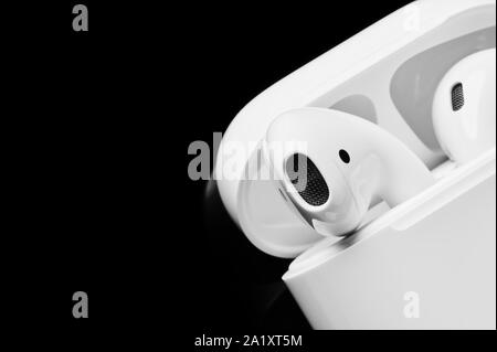 Wireless bianco gli auricolari o le cuffie in contenitore di plastica o la casella per la memorizzazione e il caricamento su sfondo nero. Close up. Foto Stock