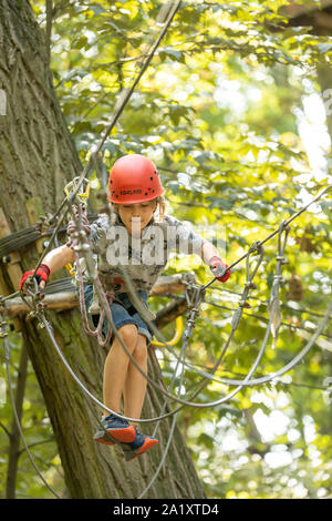 Falesia, corso di arrampicata, boy, 9 anni, con il casco e il cablaggio a un corso di arrampicata in una foresta, Foto Stock