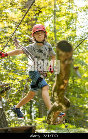 Falesia, corso di arrampicata, boy, 9 anni, con il casco e il cablaggio a un corso di arrampicata in una foresta, Foto Stock