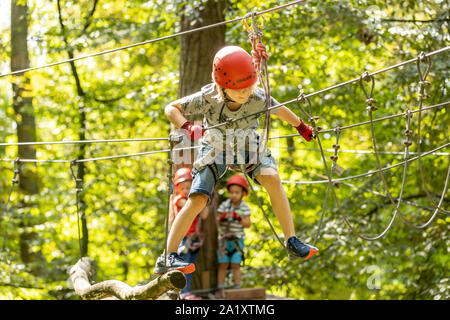 Falesia, corso di arrampicata, boy, 9 anni, con il casco e il cablaggio a un corso di arrampicata in una foresta, Foto Stock