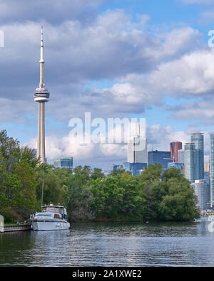 Grande piacere barca è ormeggiata lungo uno dei canali di Toronto Islands sistema con il Downtown Toronto skyline di distanza. Foto Stock