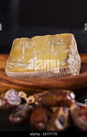 Pezzo di vecchio formaggio blu ed un ramo di date giacciono su di un piatto di legno Foto Stock