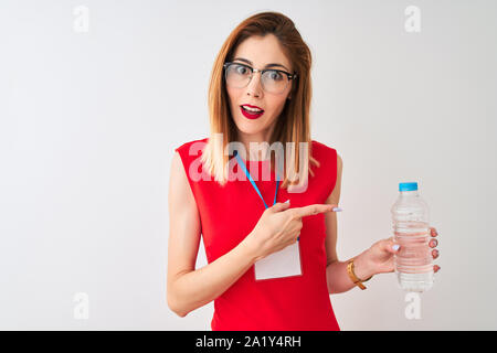 Redhead imprenditrice indossando id card acqua potabile isolato su sfondo bianco molto felice puntando con mani e dita Foto Stock