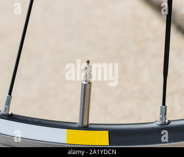 Primo piano dettaglio del pneumatico di una bicicletta stelo valvola, presta stile, in posizione di chiusura sulla strada di una ruota di bicicletta Foto Stock