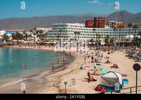 Tenerife, Spagna - Agosto, 2019: persone in spiaggia affollata con hotel in background, Costa Adeje, Tenerife, Spagna Foto Stock