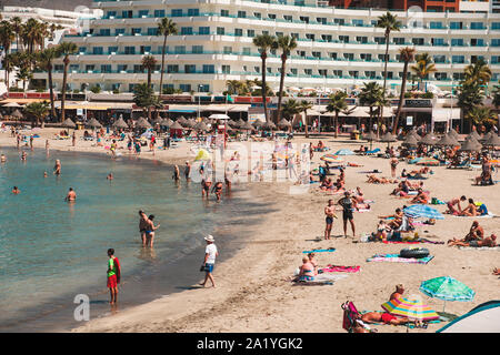 Tenerife, Spagna - Agosto, 2019: persone in spiaggia affollata con hotel in background, Costa Adeje, Tenerife, Spagna Foto Stock