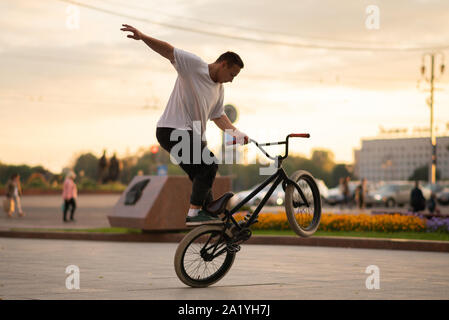 Il ragazzo esegue uno stunt su BMX, in piedi sulla ruota posteriore. Foto Stock