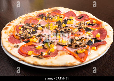 Pizza con salsiccia per pizza e funghi, prosciutto e peperoni dolci. Foto Stock