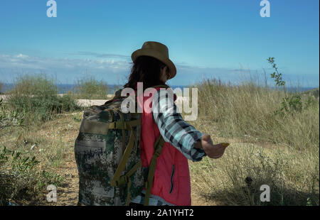 Ragazza traveler passeggiate attraverso il campo e trattiene la sua mano. Seguimi Foto Stock