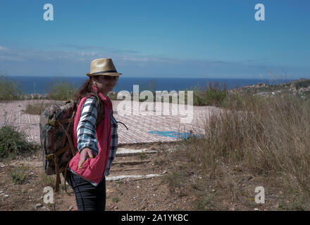 Una giovane donna traveler passeggiate attraverso il campo per la piattaforma di osservazione e trattiene la sua mano. Seguimi Foto Stock