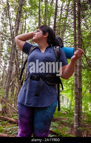 Persona guardando il cielo nel bosco cercando di decidere dove andare Foto Stock