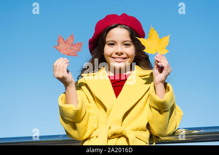 Ispirando caduta. Idee per il tempo libero d'autunno. Bambina adorare la stagione autunnale. Kid tenere foglie di acero. Piccola ragazza indossare abbigliamento cadere all'esterno. Autunno lista della benna per bambini. Cielo chiaro e di buon tempo. Foto Stock