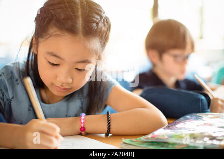 Sorridente scuola elementare i ragazzi in classe Foto Stock