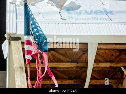 Un strappata bandiera americana pende da un condominio danneggiato dall' uragano Michael in 2018, Sett. 27, 2019, in Messico Beach, Florida. Foto Stock