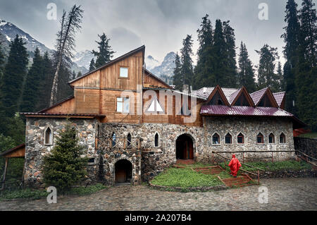 Donna della pioggia rossa manto di copertura in prossimità del vecchio castello nella valle di montagna Foto Stock