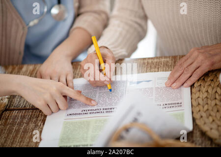 Titolare di pensione o di rendita sottolineando alcune parole in un giornale Foto Stock