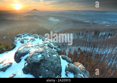 Molla blu lo spuntar del giorno, lo scongelamento di ultima neve. Scogliera di arenaria al di sopra di una profonda valle nebbiosa. Foto Stock