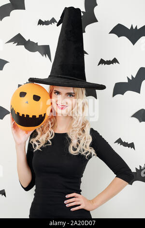 Ritratto di fiduciosa piuttosto giovane donna in costume maga che mostra il palloncino arancione con occhi dipinti e spaventoso sorriso toothy Foto Stock