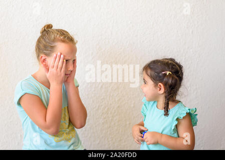 Scioccato adolescente ragazza e sua sorella toddler contro uno sfondo bianco. Emotional sorpreso inorridito razza mista di bambini. Foto Stock