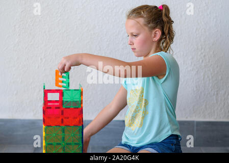 Bella ragazza adolescente giocando con un sacco di colorati di materia plastica in blocchi costruttore e costruisce la casa. Foto Stock