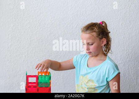 Bella ragazza adolescente giocando con un sacco di colorati di materia plastica in blocchi costruttore e costruisce la casa. Foto Stock