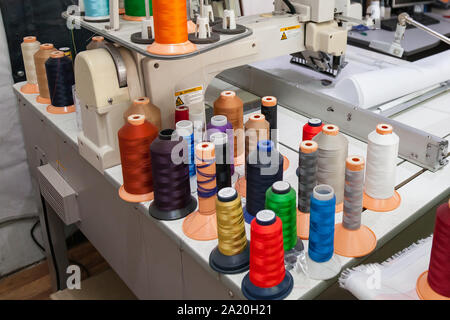 Un gran numero di bobine con fili colorati in un laboratorio di cucito e di salpamento tessili per il settore automotive e industria Foto Stock