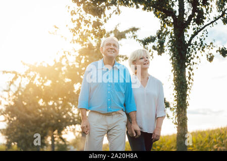 Senior donna e uomo avente una passeggiata lungo il percorso in campagna Foto Stock